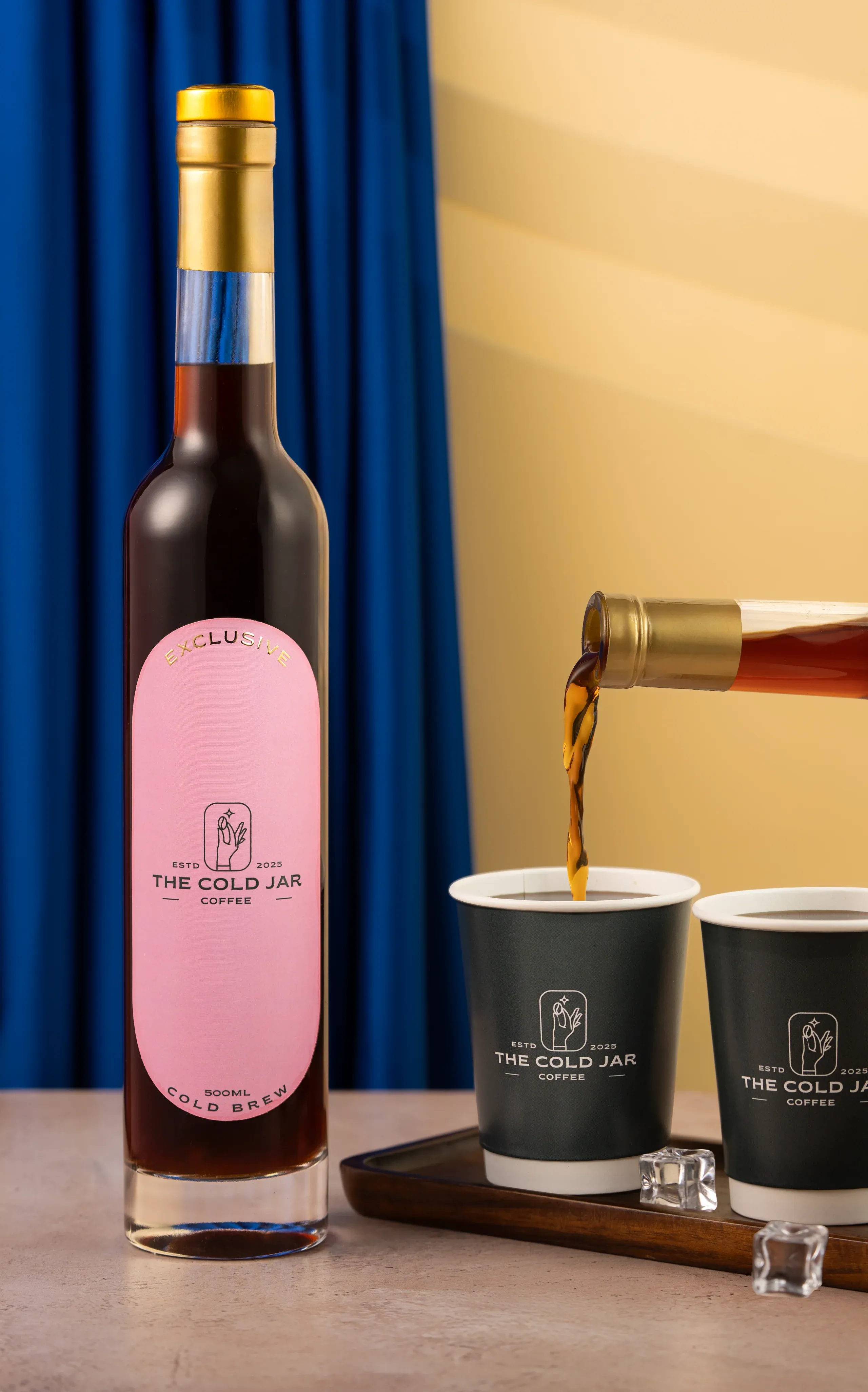 The Cold Jar cold brew poured from the gold bottle into branded cups, by MIROIR Studio